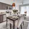 A modern kitchen with dark cabinetry and a kitchen table with cloth chairs.